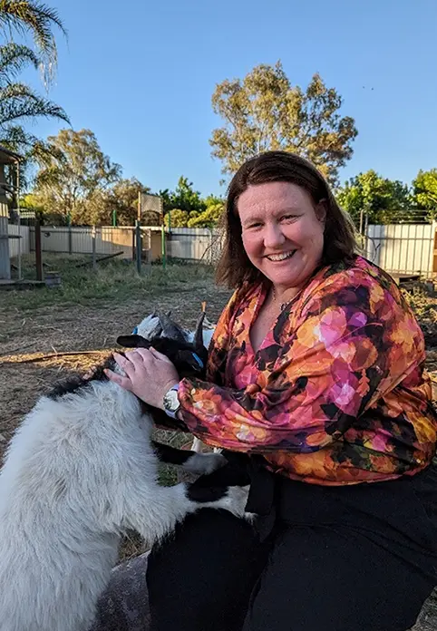 Person crouched down patting goat