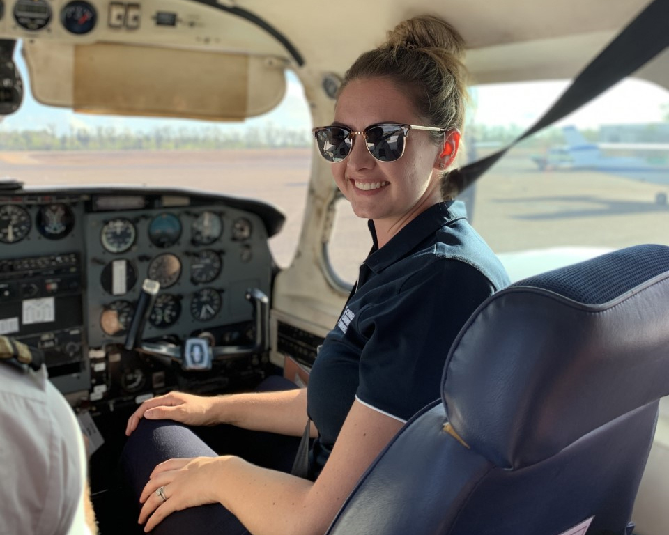 Woman sitting in the front seat of a small plane, smiling.
