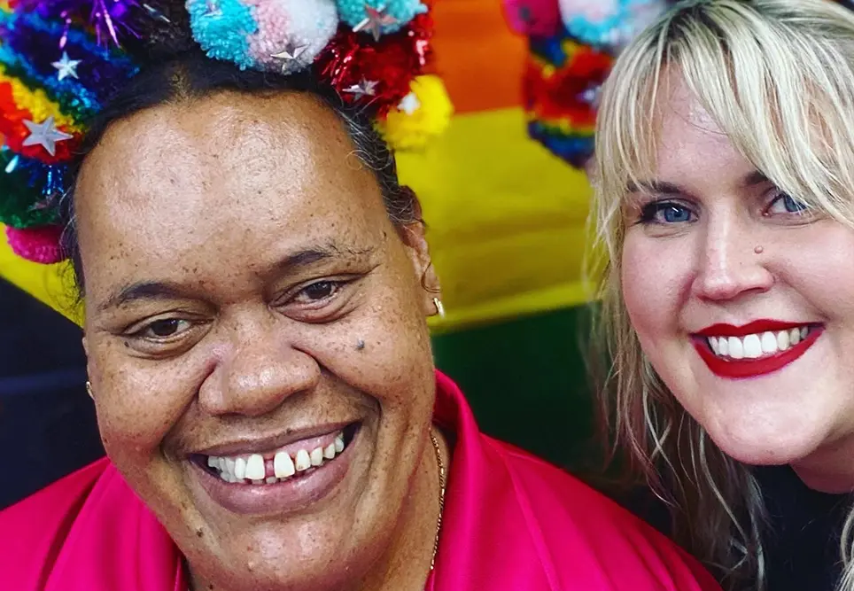 two people smiling with colourful pompom headbands on