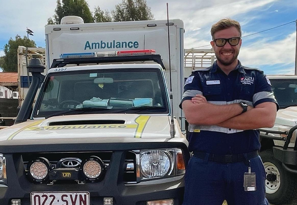 Person with arms crossed smiling next to ambulance