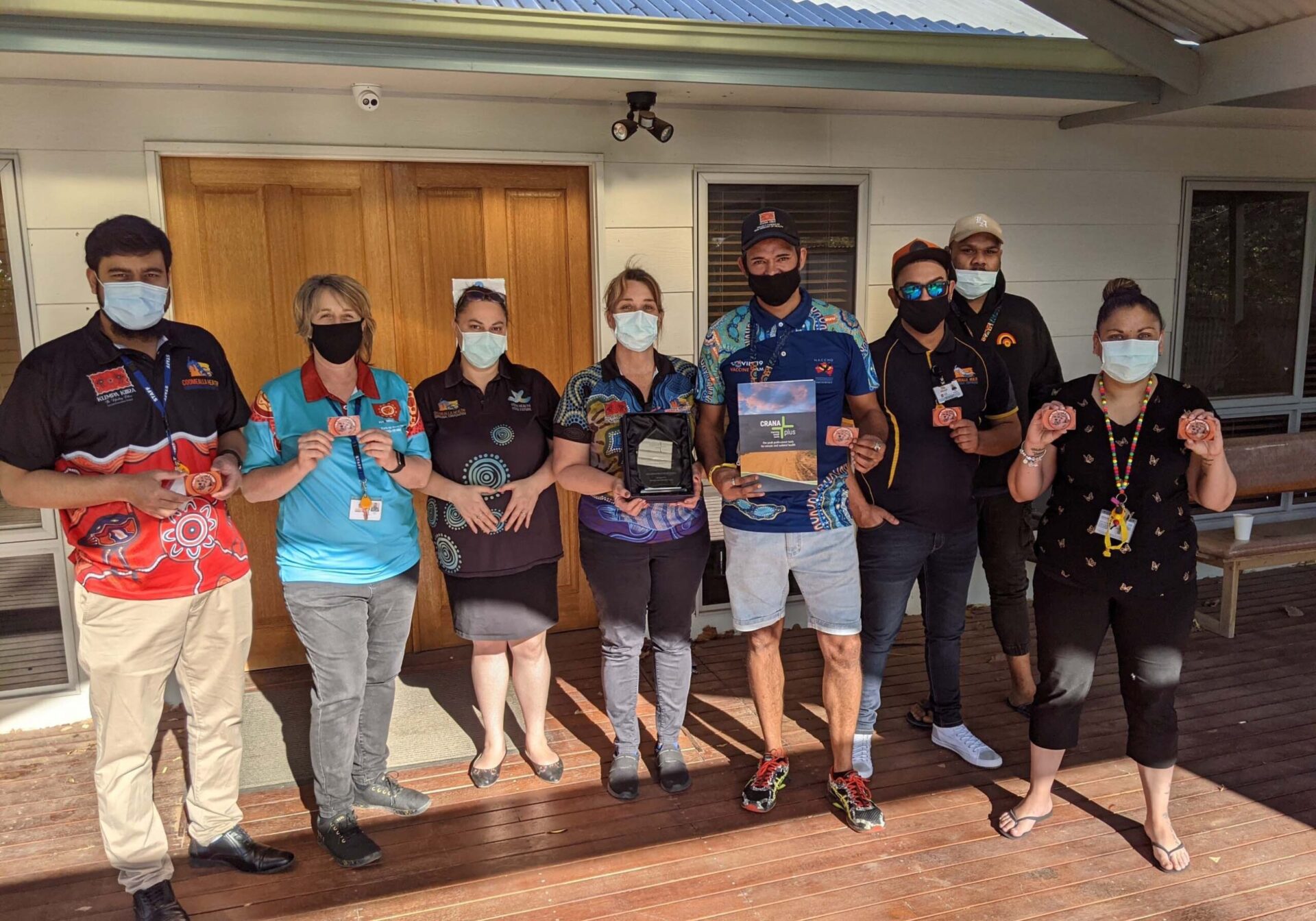 Group of health professionals standing on deck, holding materials.