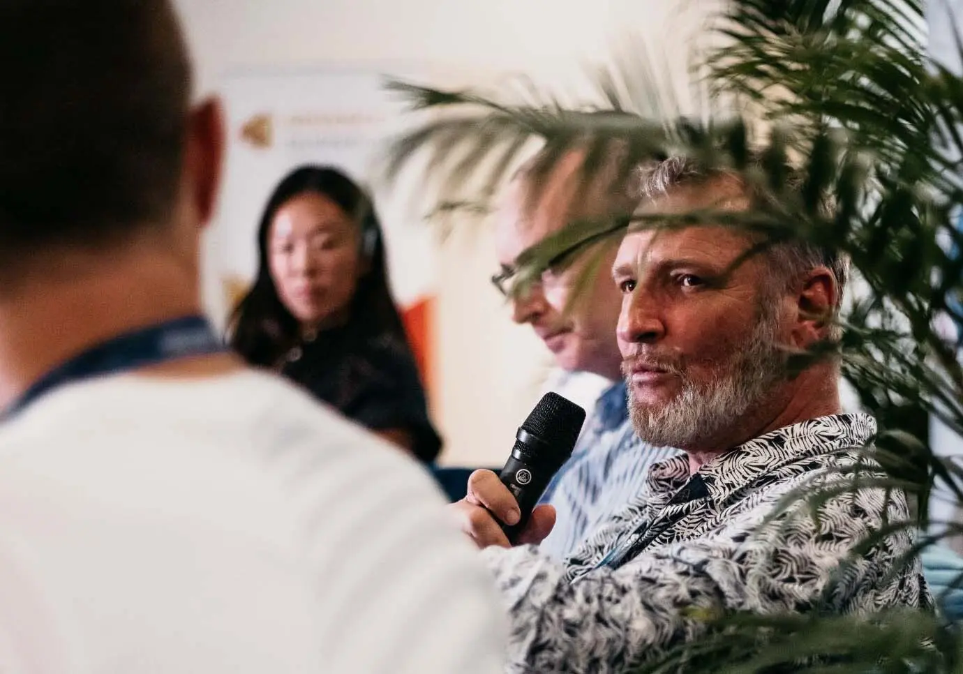 Man holding a microphone and listening to someone.