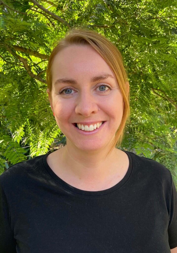 Stephanie Cooper. Stephanie has red hair pulled back, is wearing a black tshirt, and is smiling.